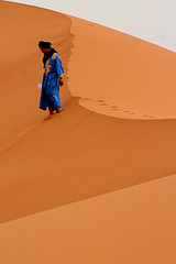 man walking on desert dunes